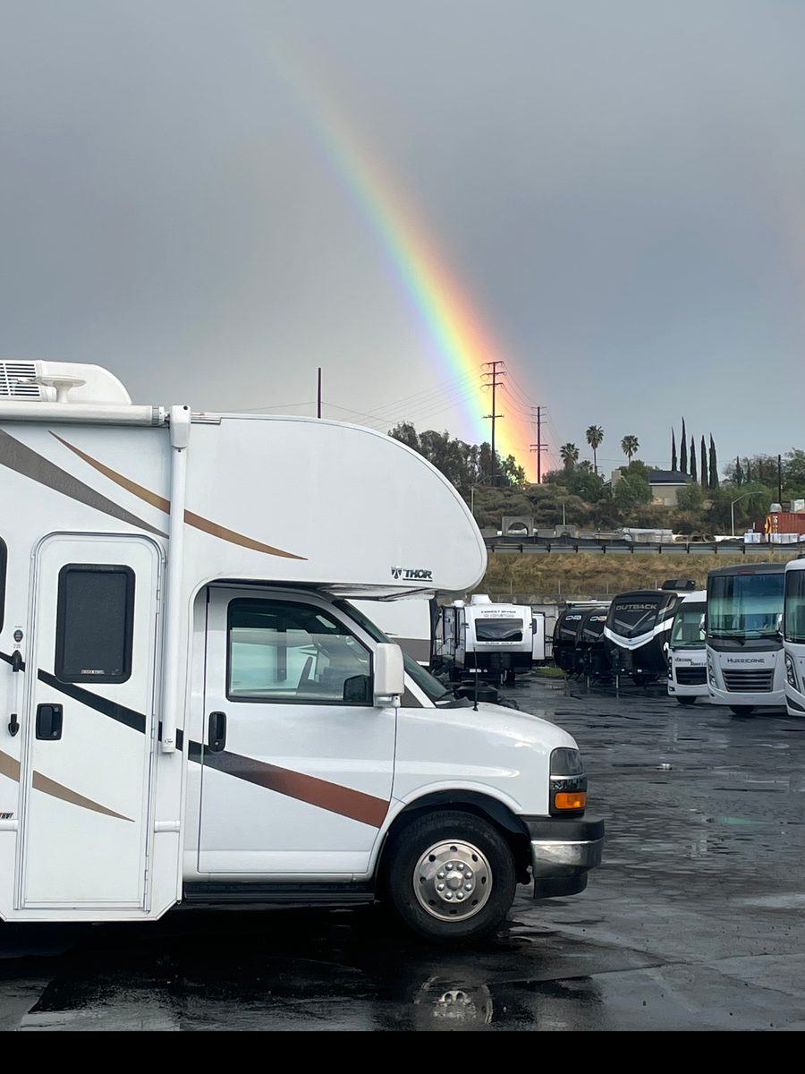 Class C motorhome under a rainbow at an RV lot